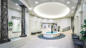 A spacious lobby with marble columns, a central fountain, and a staircase leading to upper floors. - Milano Serviced Apartments (Melbourne)
