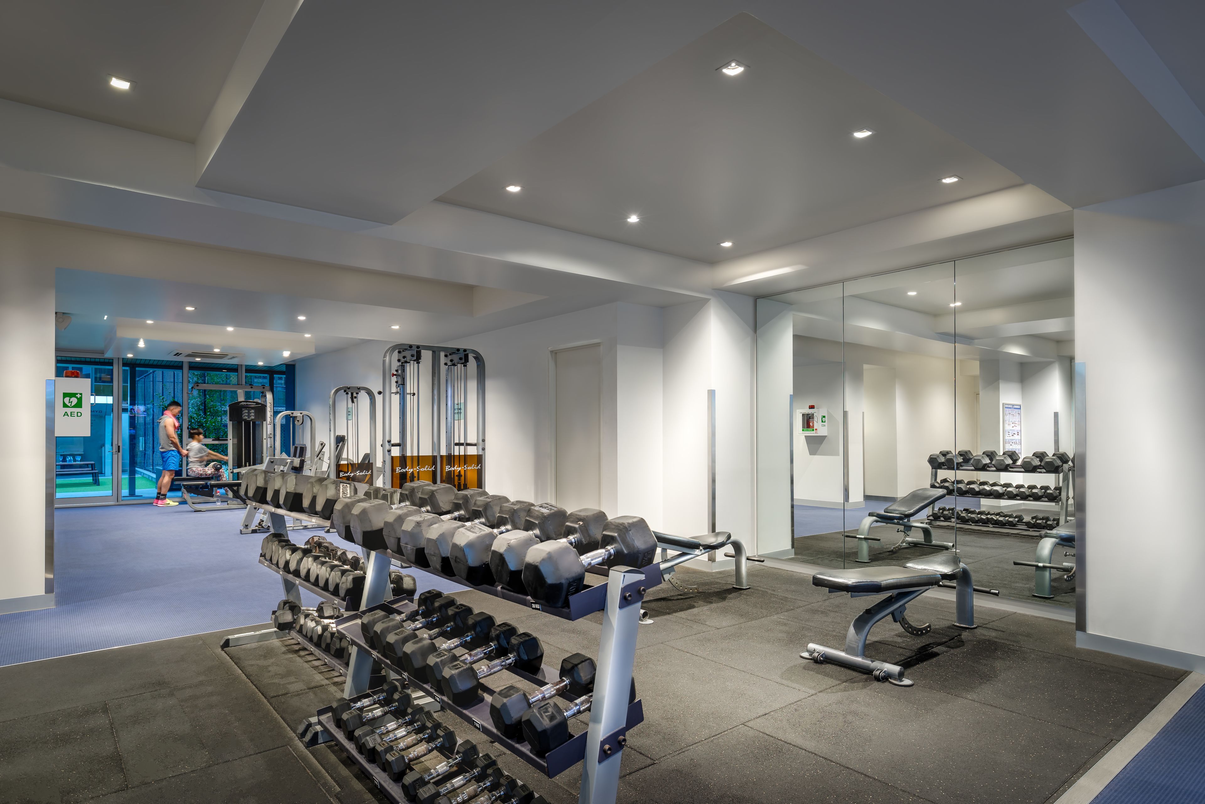 Un gimnasio moderno con diverso equipo de levantamiento de pesas, incluyendo mancuernas y bancos.