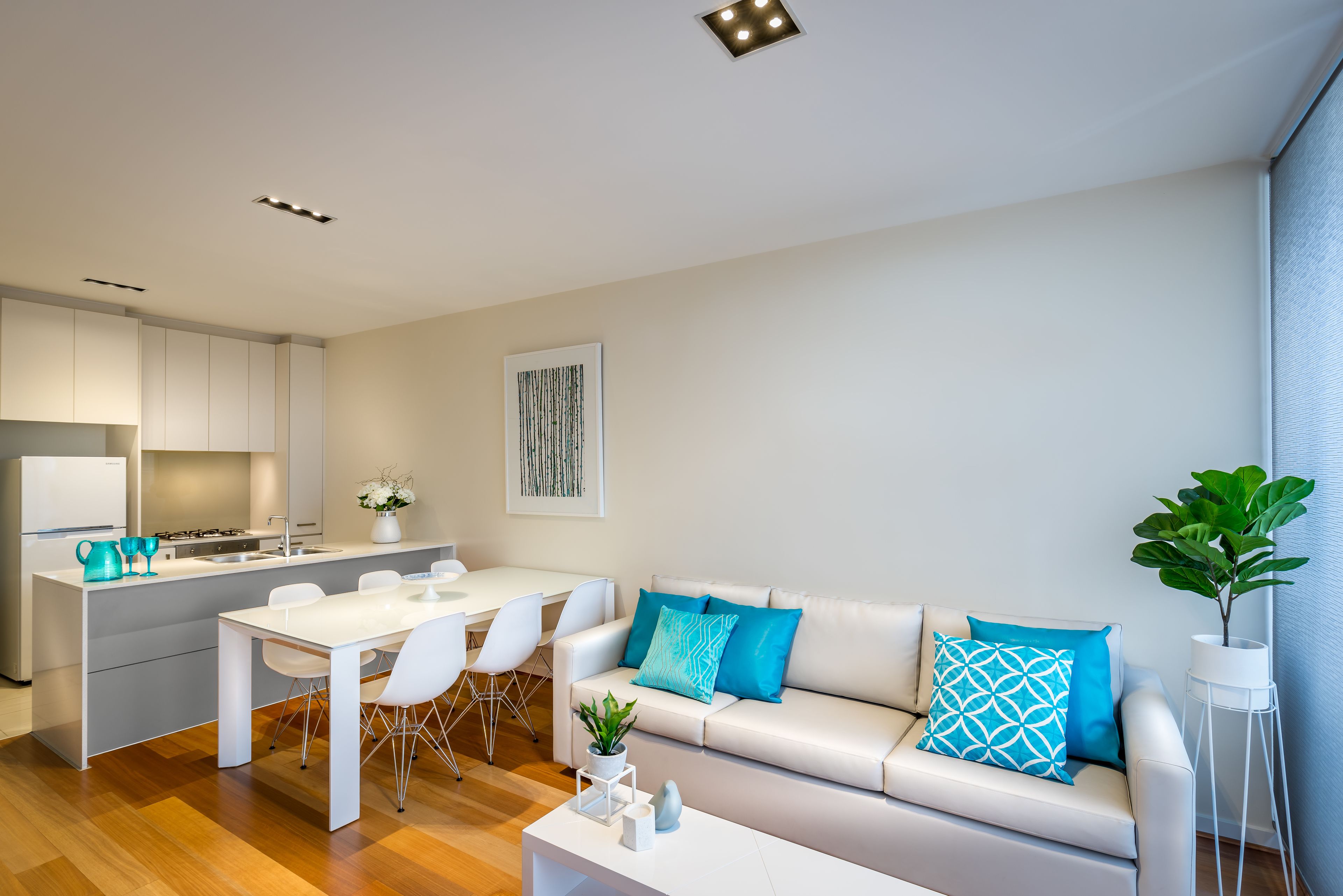 A modern, well-lit living area with a kitchen, dining table, and sofa.