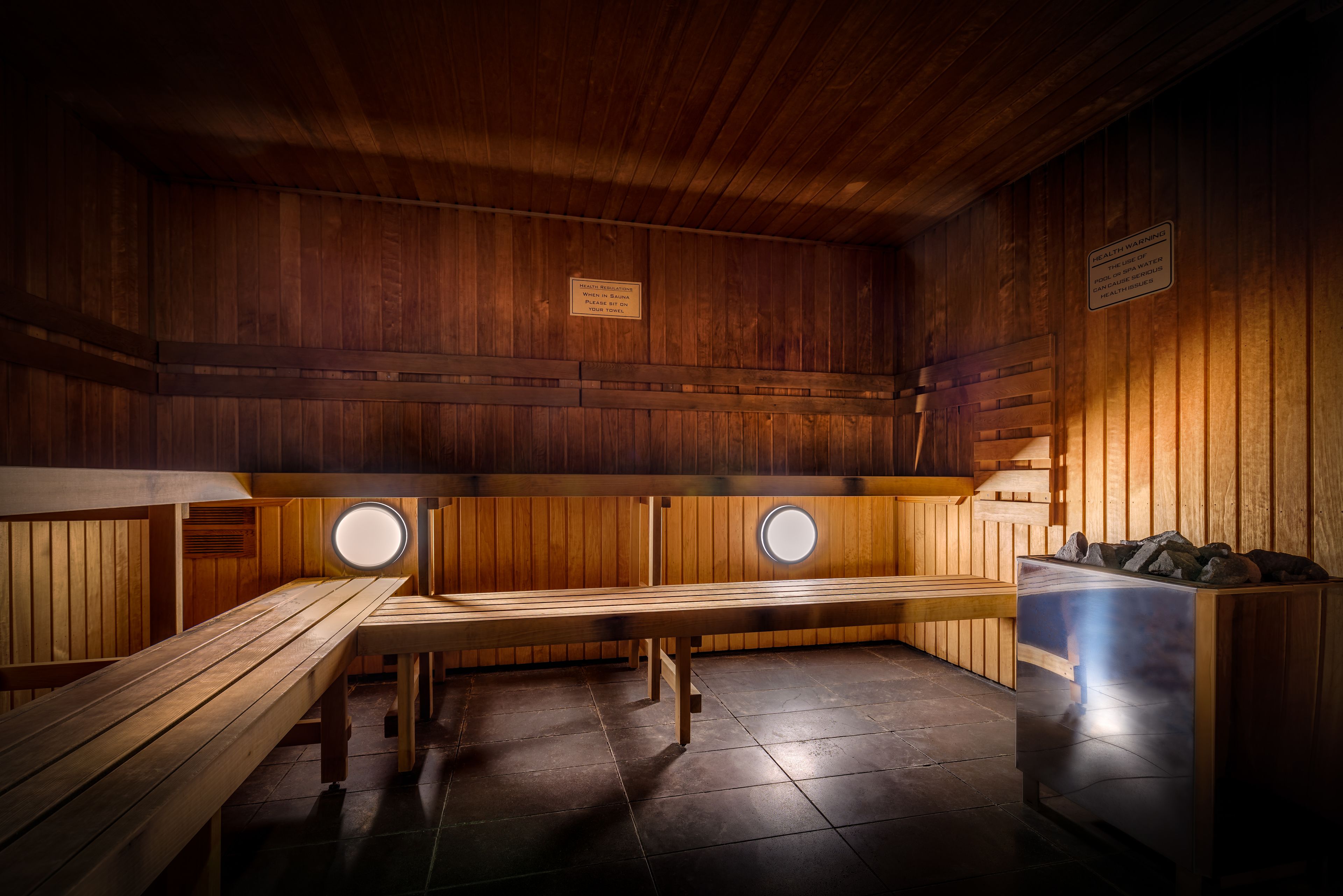 Un cuarto de sauna con bancos de madera, una unidad de sauna y una pared de madera con un letrero.