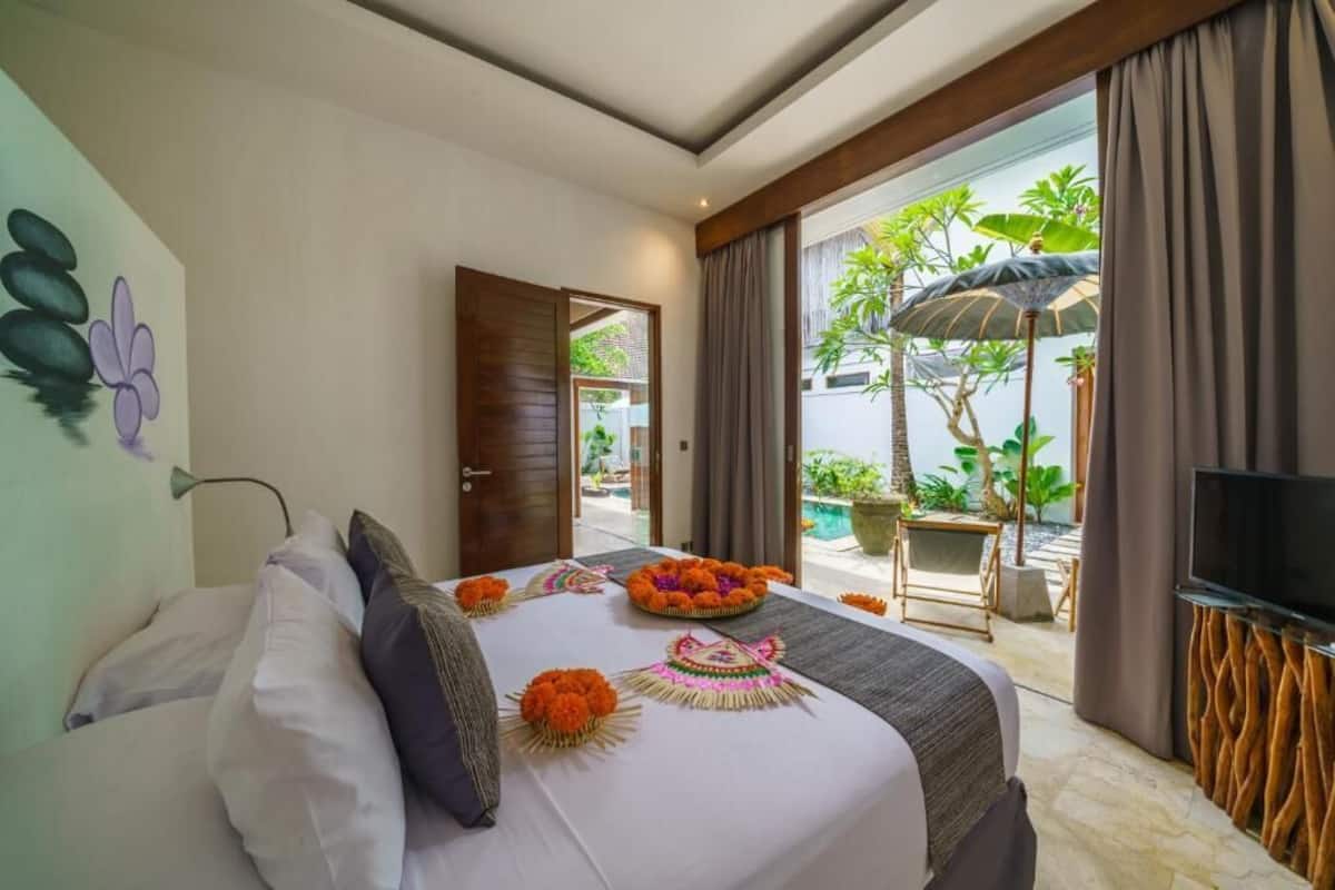 A hotel room with a bed, a TV, and a view of the outdoor area.