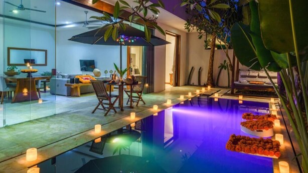 Un área de piscina interior moderna con zona de comedor y pared de vidrio.