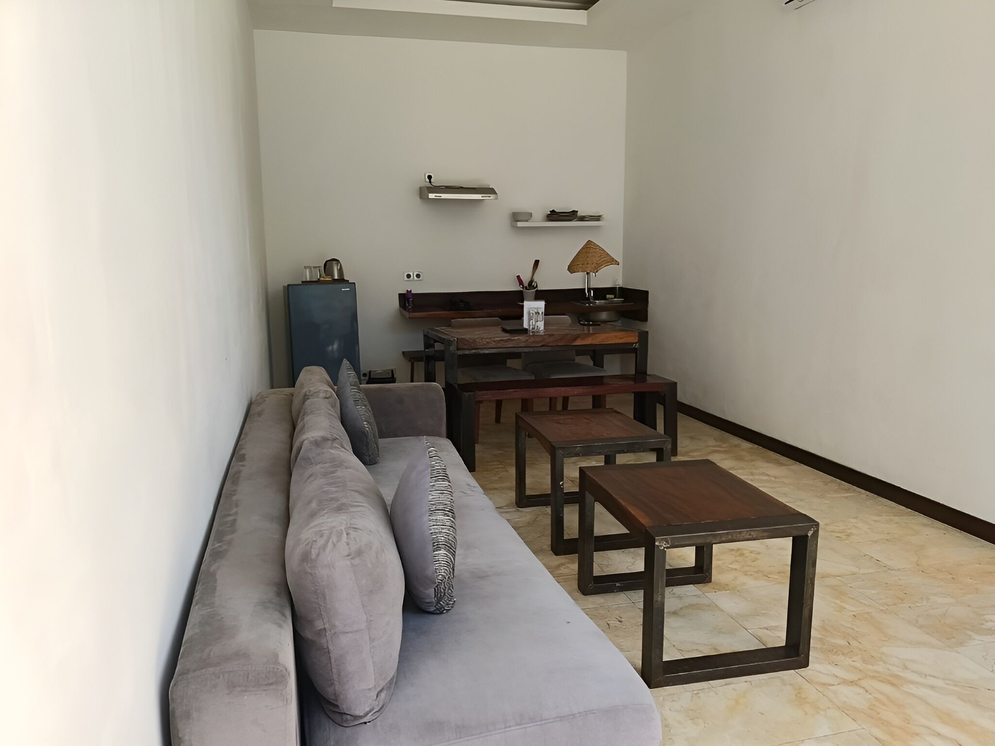Ein modernes Wohnzimmer mit grauem Sofa, Couchtisch aus Holz und einem Essbereich mit Holztisch und Stühlen.