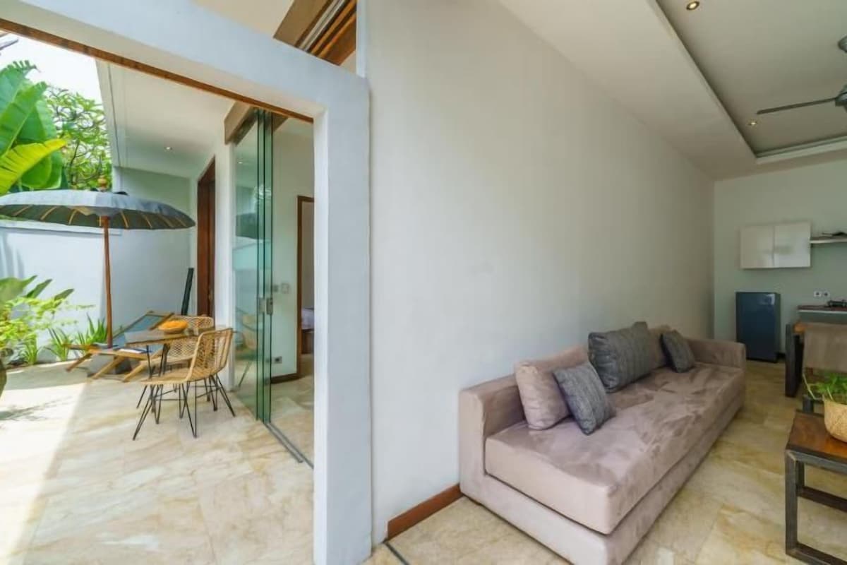 Un espacio de sala moderno con un sofá, una mesa de comedor y una cocina al fondo.