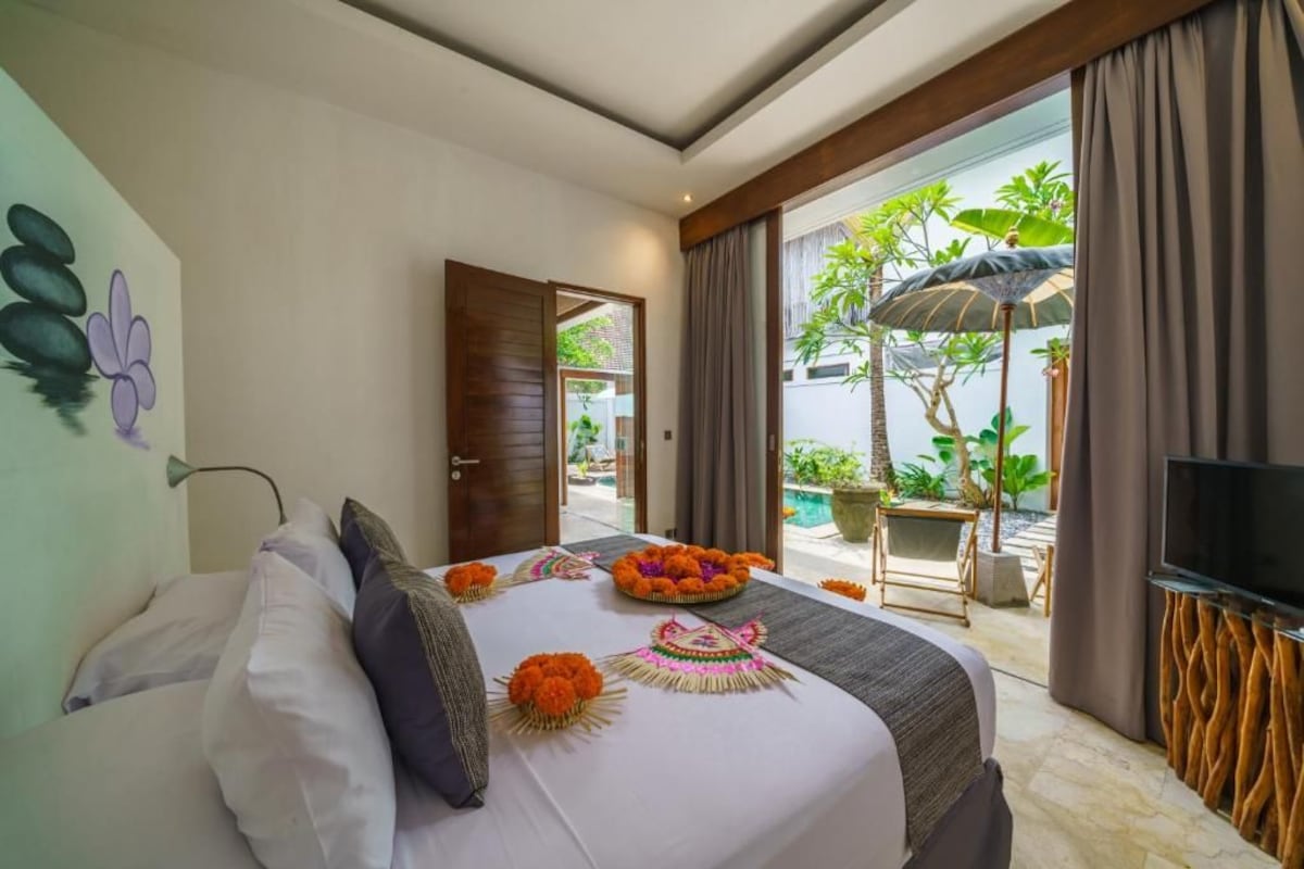Habitación de hotel con cama, televisión y vistas al exterior.