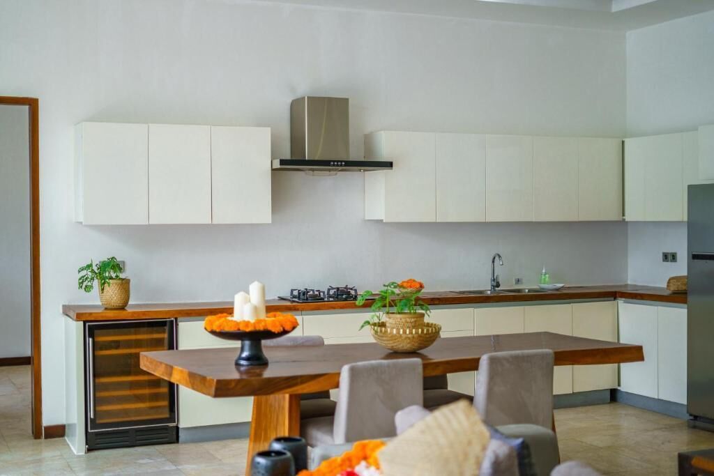 Una cocina moderna con armarios blancos, una isla de madera y una campana extractora de acero inoxidable.