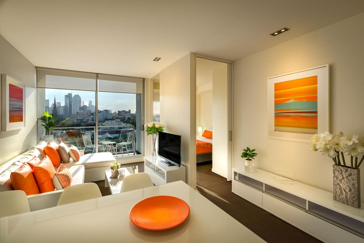A modern living room with a city view, a dining area, and a bedroom with a cityscape view.