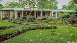 A two-story building with a green roof, surrounded by lush greenery and a well-maintained garden. - Villa 33 (Blantyre)