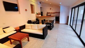 A modern living room with a sofa, a wooden coffee table, and a dining area with chairs and a table. - Villa 33 (Blantyre)