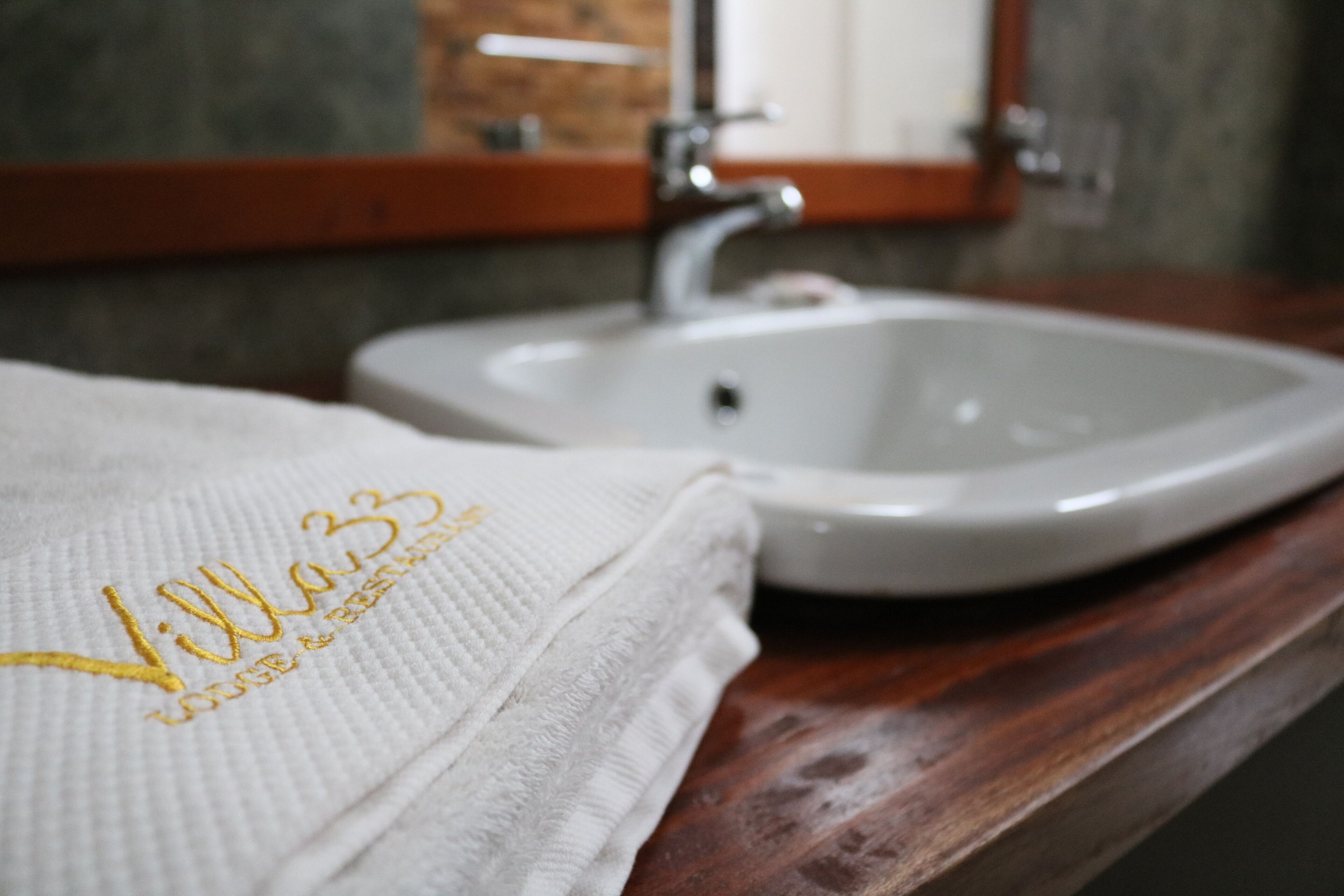 Ein Badezimmer mit einem weißen Waschbecken, einer Holzauslage und einem Handtuch mit Stickereien.