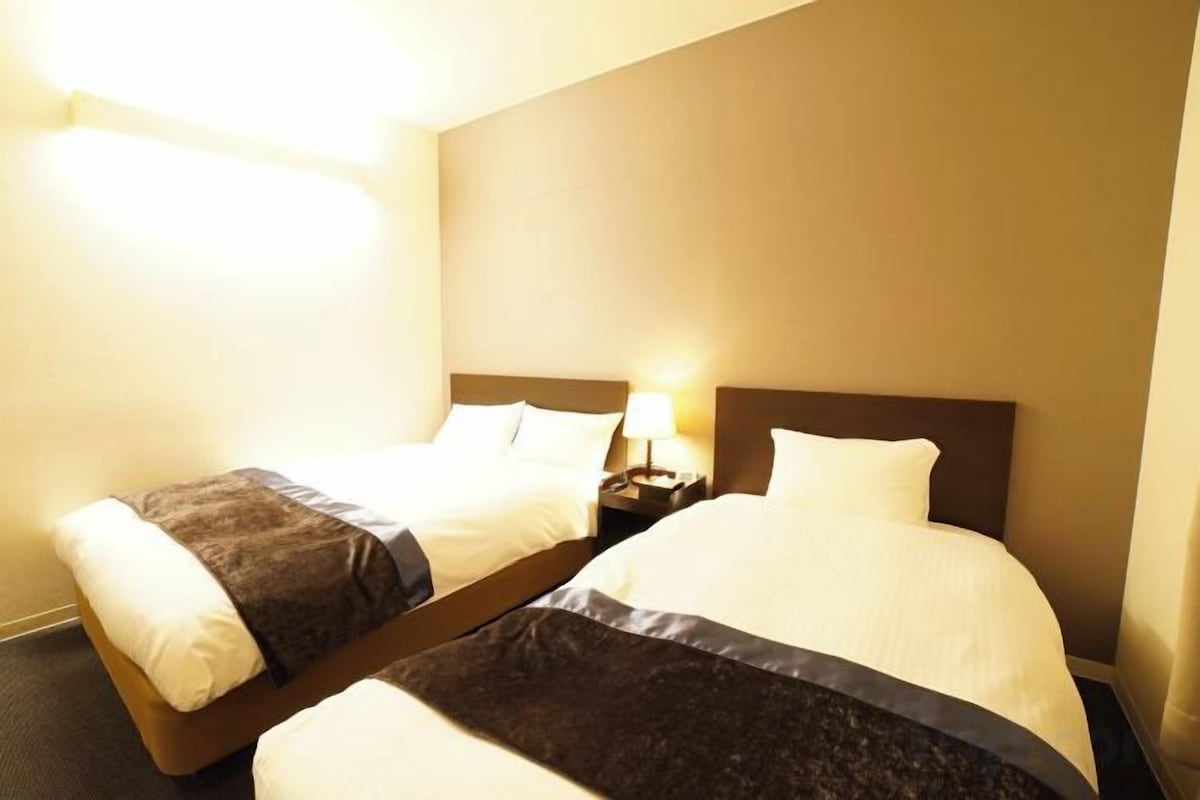 Une chambre d’hôtel avec deux lits, chacun étant équipé d’une table de chevet et d’une lampe.