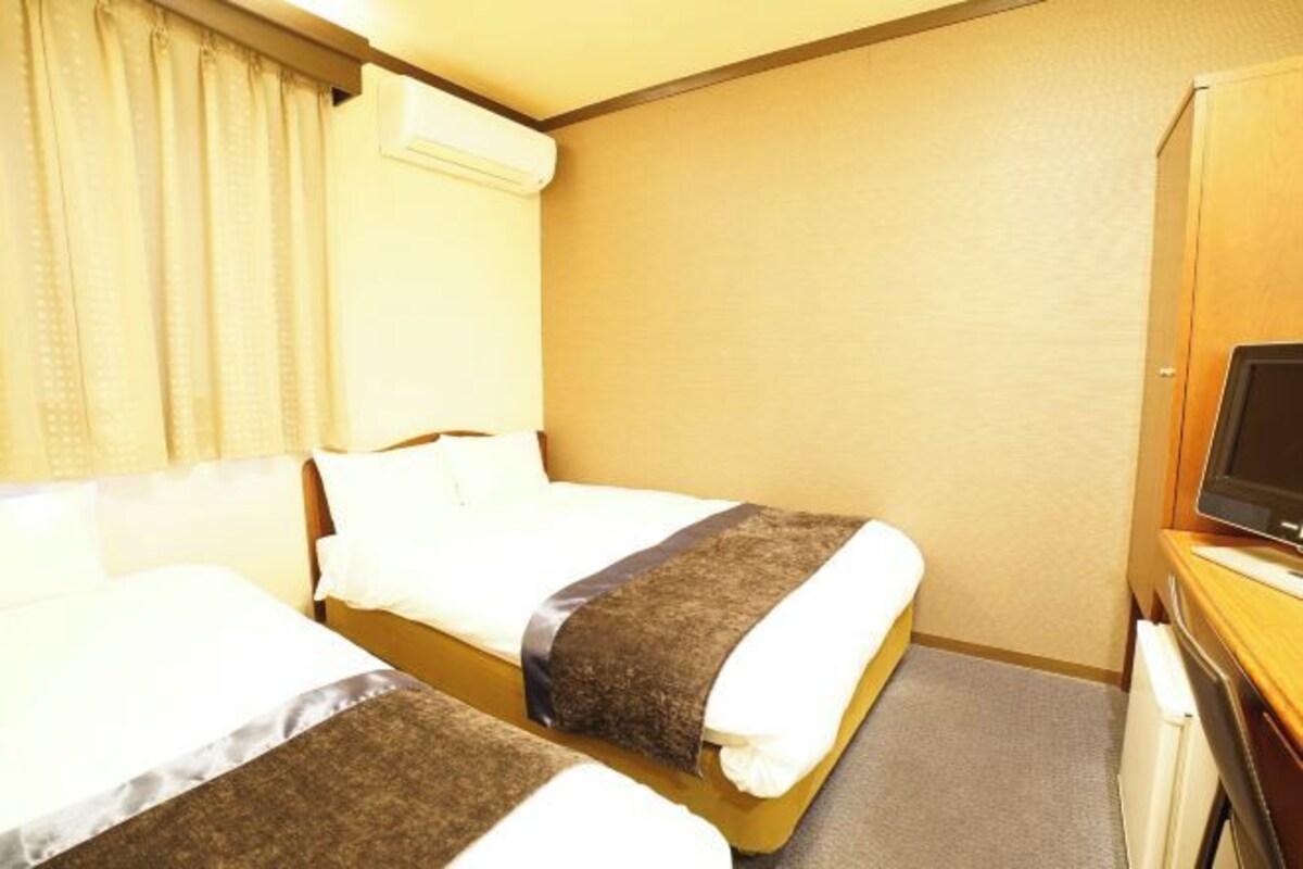 A hotel room with two beds, a television, and a small desk.