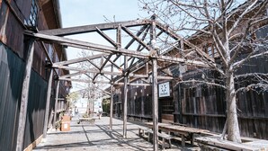 Un espace extérieur abrité, doté de bancs en bois et d’une structure métallique.