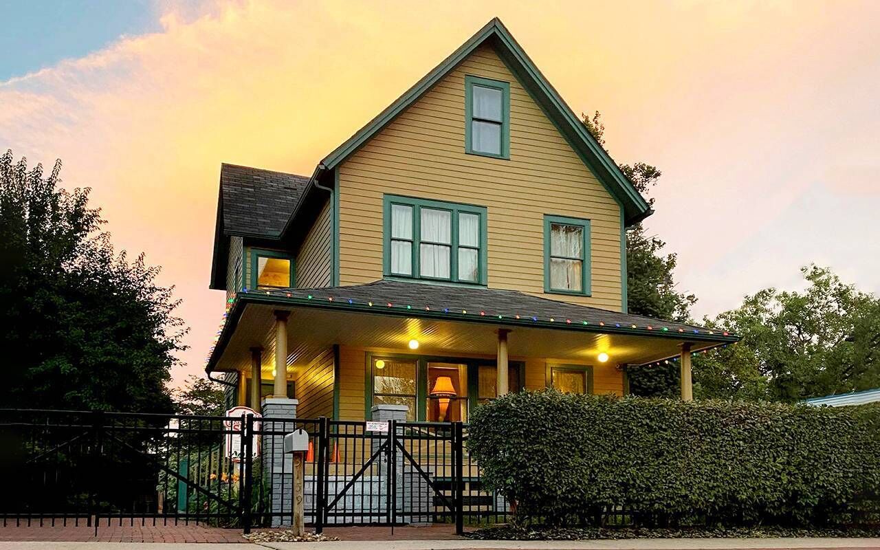 A two-story house with a porch, a front gate, and a mailbox.