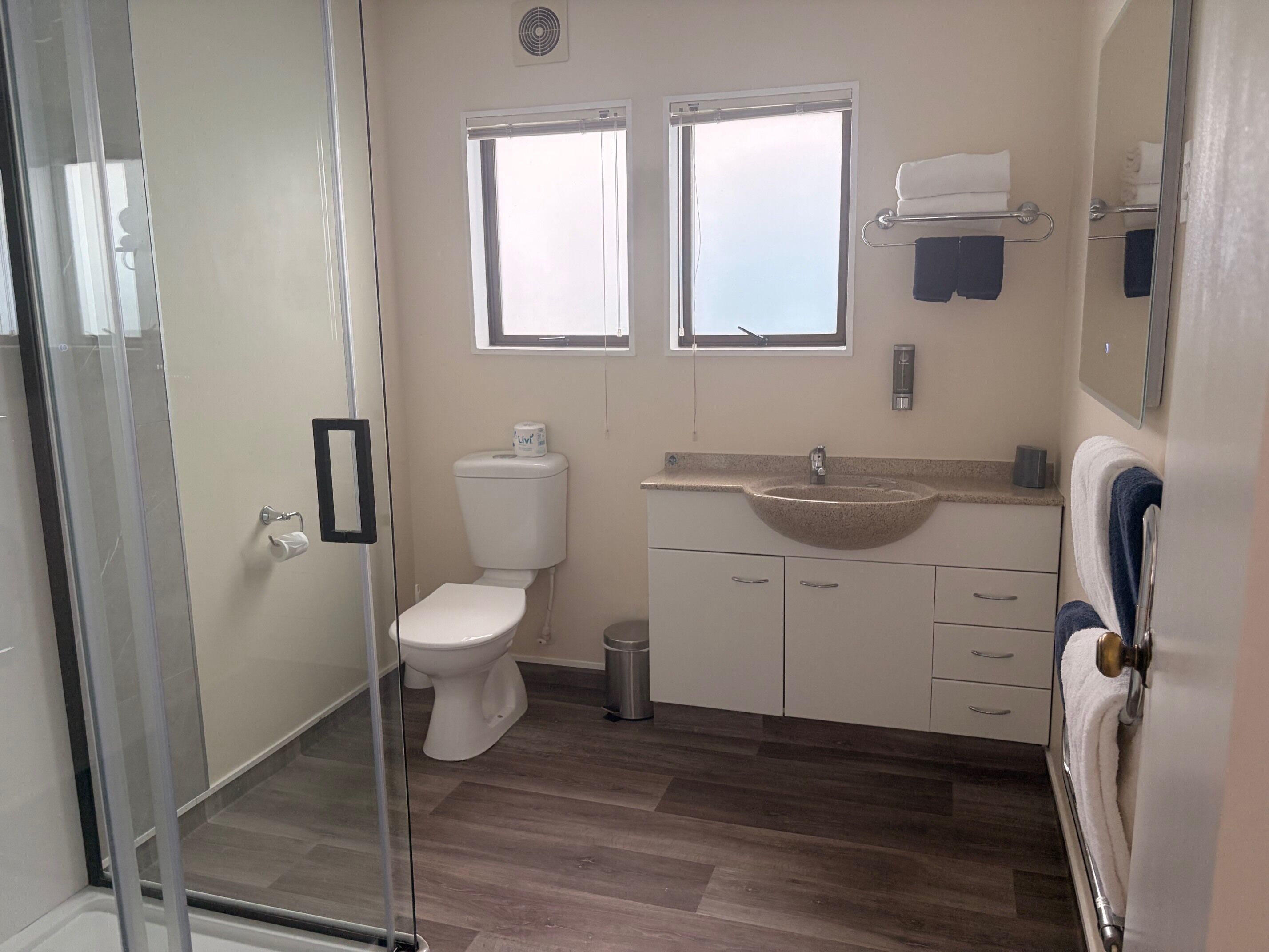 Baño con inodoro, lavabo y cabina de ducha de vidrio.