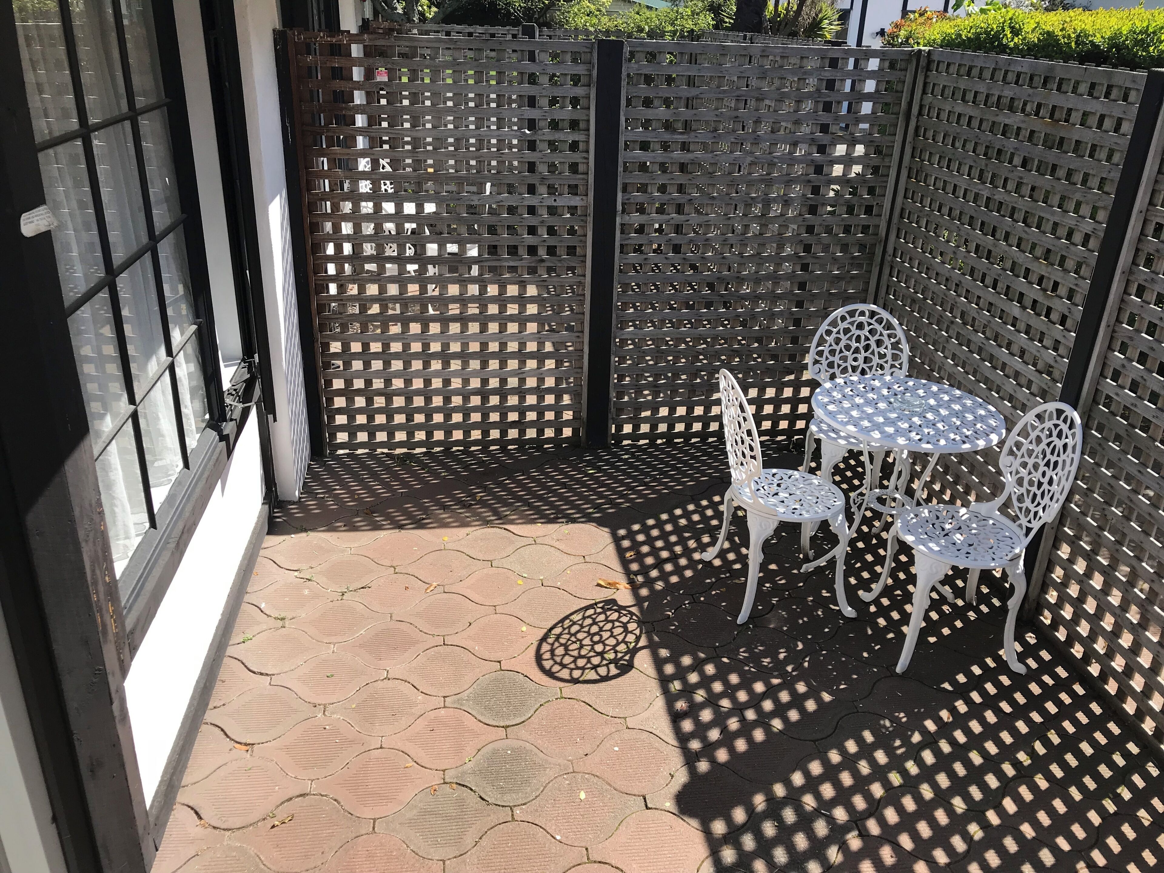 A patio area with a lattice fence, a small table with chairs, and a door with a window.