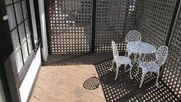 A patio area with a lattice fence, a small table with chairs, and a door with a window.