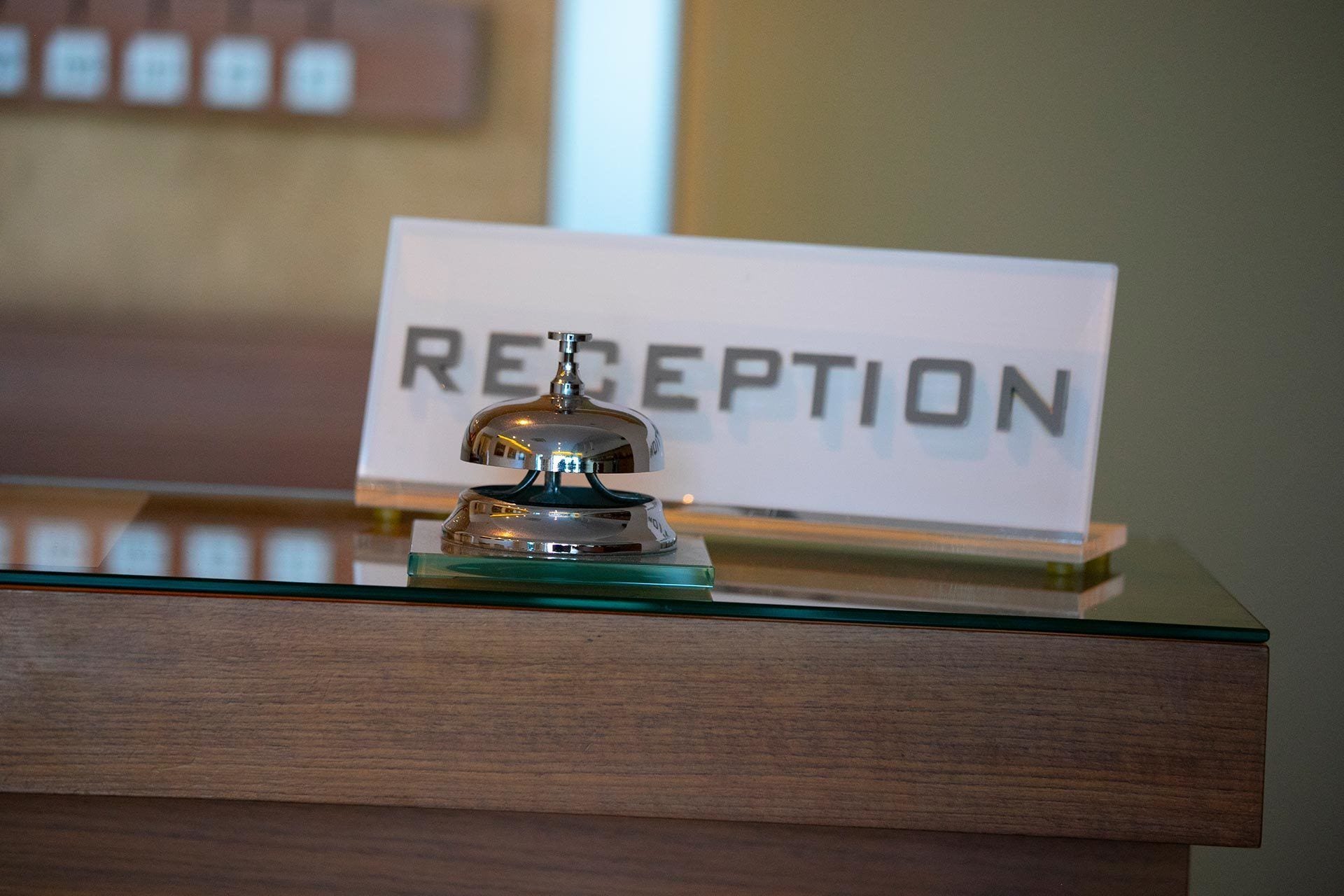 A reception area with a glass counter, a bell, and a sign that reads "RECEPTION".