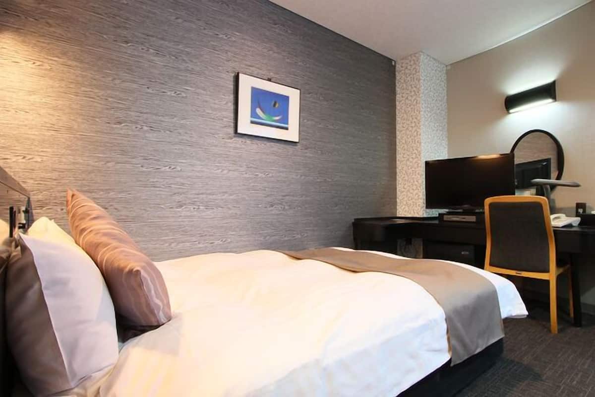 A hotel room with a bed, a desk, a chair, a television, and a picture on the wall.