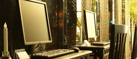 A computer desk with two monitors, a keyboard, and a candle.