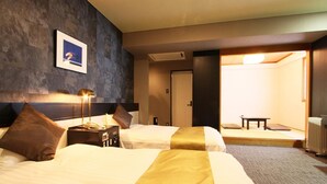 Habitación de hotel con dos camas, una mesita de noche con lámpara, un cuadro en la pared y vistas a una estancia tradicional japonesa.