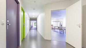 Un pasillo con puertas, un banco y vistas a otra habitación.