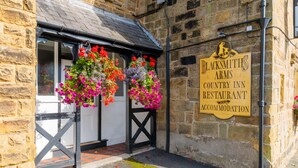 Un edificio de piedra con un cartel que indica Blacksmiths Arms Country Inn y Alojamiento.