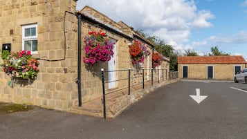 Un edificio de piedra con macetas de flores en las ventanas y una calle despejada al frente.