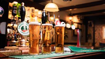 Three glasses of beer on a bar counter with a tap labeled "Timothy Taylors Landlord" and "Carling."