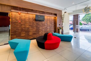 A modern lobby with a wooden wall, a flat-screen TV, and colorful seating.