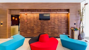 A modern reception area with a wooden wall, a flat-screen TV, and two blue sofas. - Dolphin Hotel, Chow Kit Kuala Lumpur (Kuala Lumpur)