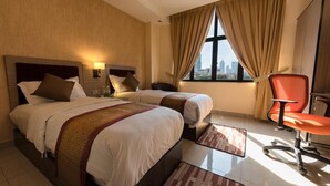 A hotel room with two beds, a desk, a chair, and a large window with a city view. - Dolphin Hotel, Chow Kit Kuala Lumpur (Kuala Lumpur)