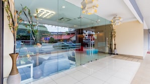 A modern hotel lobby with a glass partition, a large vase with flowers, and a reflection of the street outside. - Dolphin Hotel, Chow Kit Kuala Lumpur (Kuala Lumpur)