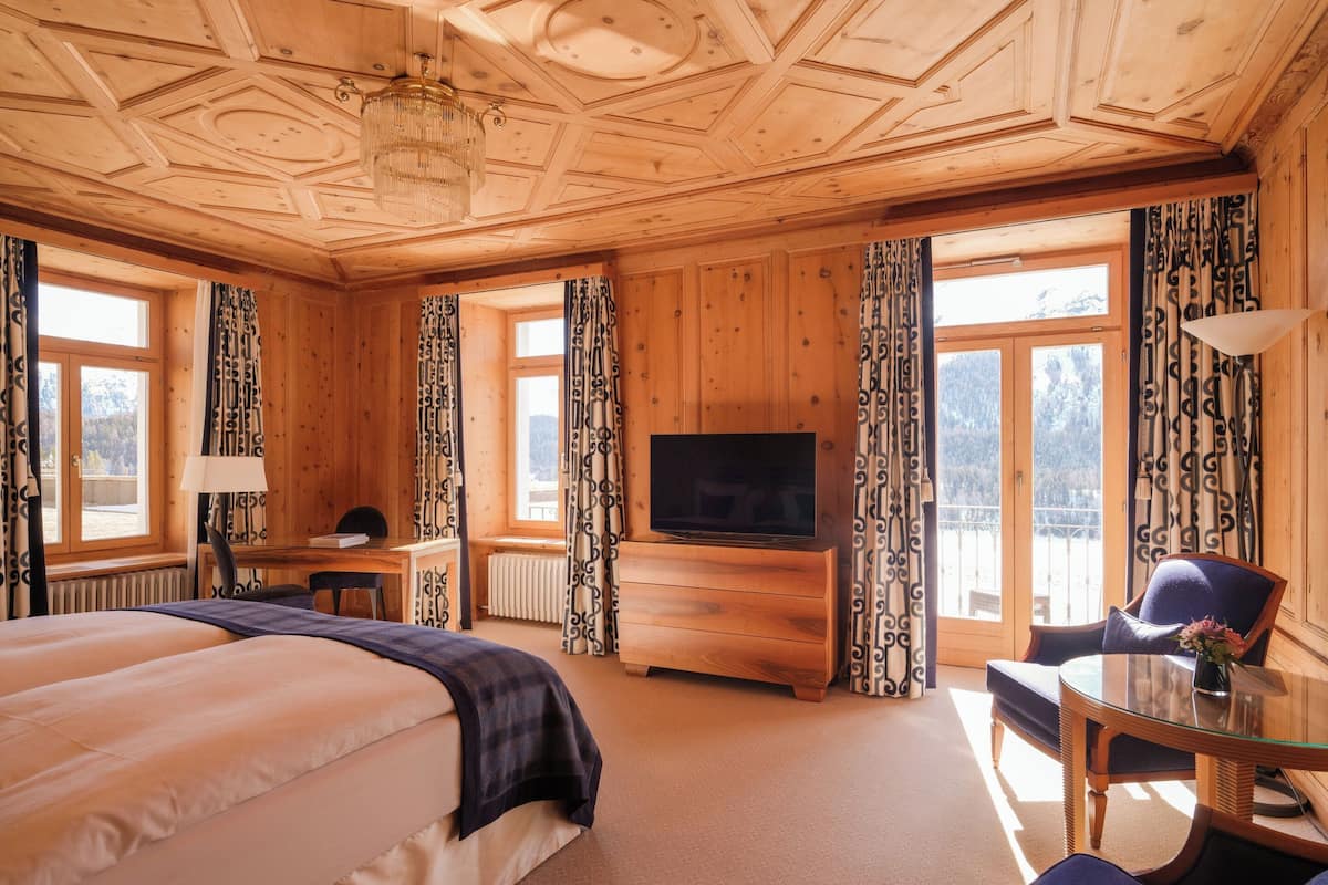 A wooden room with a bed, a desk, a TV, and a chair.