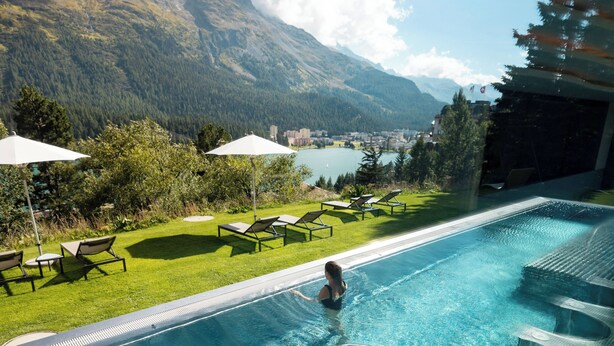 A swimming pool with lounge chairs and umbrellas, overlooking a lake and mountains. - Kulm Hotel St. Moritz (St. Moritz)