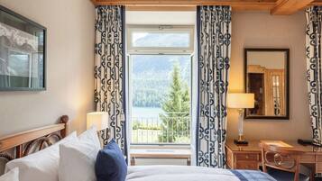 A hotel room with a bed, a desk, a chair, and a large window with curtains.