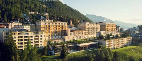 Un complejo hotelero con varias edificaciones, rodeado de vegetación exuberante y montañas al fondo.