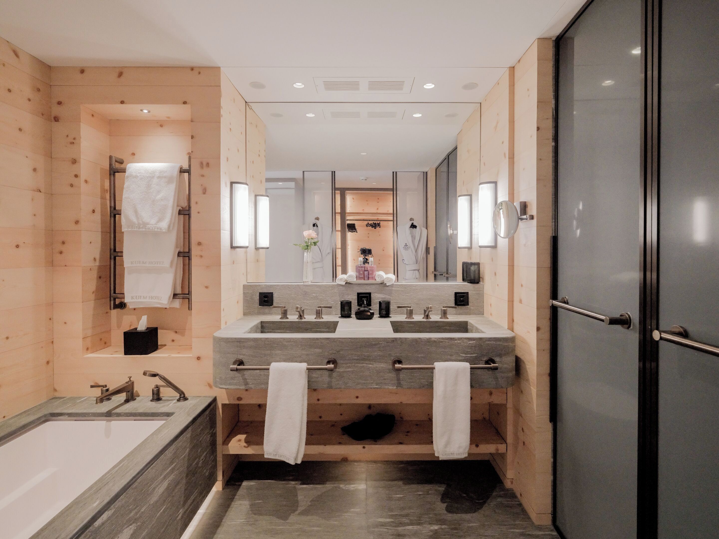 Un baño moderno con un espejo grande, dos lavamanos y una bañera.