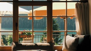 A room with a large arched window overlooking a lakeside view with outdoor seating. - Kulm Hotel St. Moritz (St. Moritz)