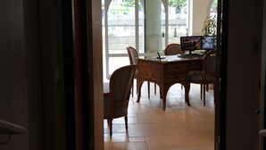 Vista interior de un comedor con una mesa, sillas, una computadora y vistas a través de un ventanal.