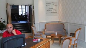 Un hall de hotel con mostrador de recepción, zona de estar y una pared con directorio.