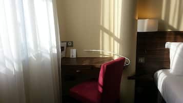 A hotel room with a desk, chair, and bed.