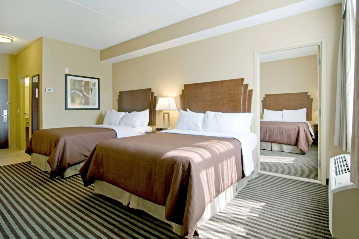 A hotel room with two beds, a large mirror, and a striped carpet.