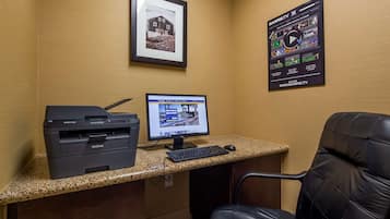 Un espacio de trabajo con una impresora Brother, un monitor Acer y una silla de cuero negra.