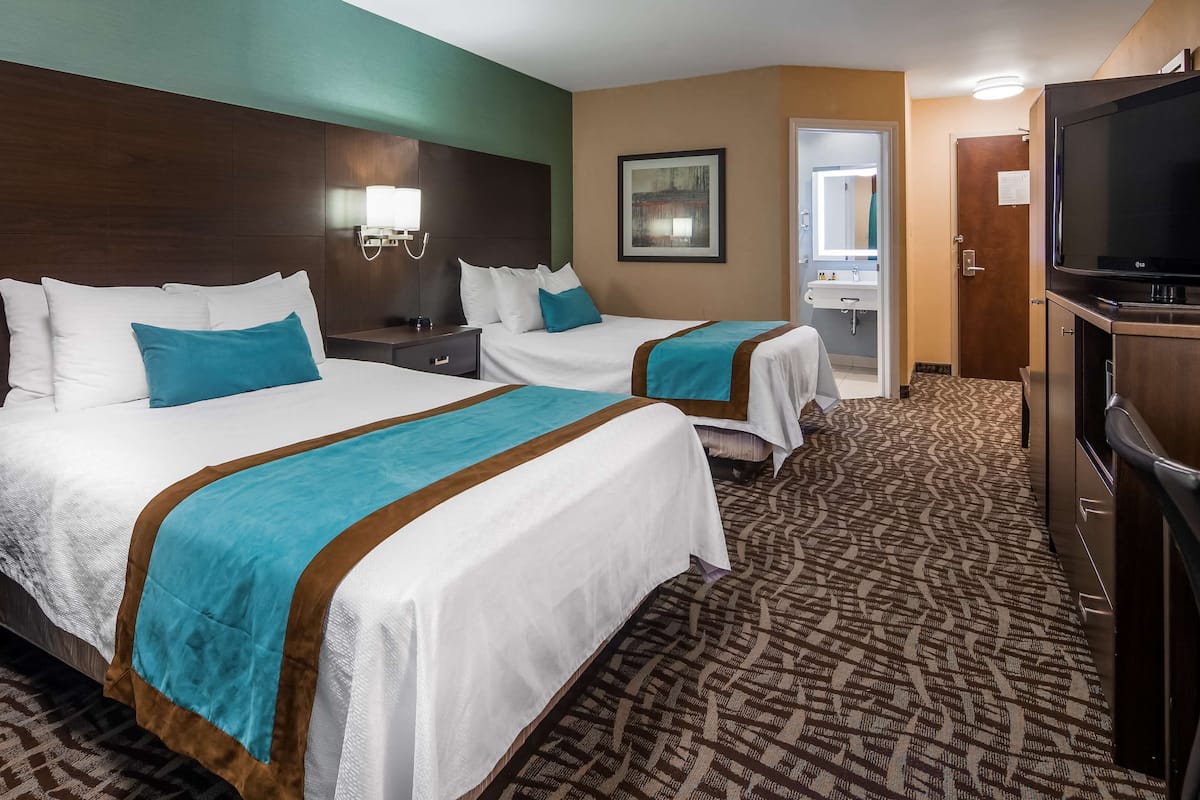 A hotel room with two beds, a TV, a desk, and a chair.