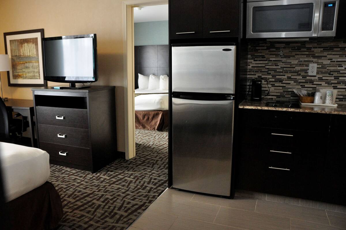 A hotel room with a bed, a TV, a refrigerator, a microwave, and a kitchenette.