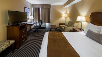 A hotel room with a bed, a desk, a chair, a TV, and two lamps.