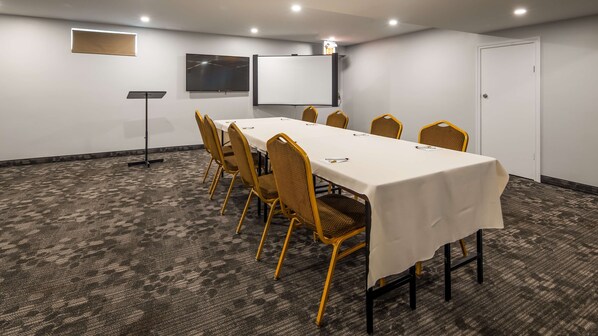 A conference room with a long table, chairs, a projector, and a screen.