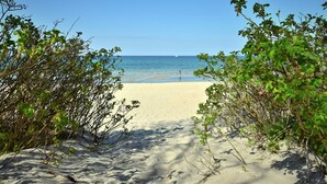 A sandy beach with a clear view of the ocean and a distant sailboat. - Hotel Residenz Waldkrone (Kuehlungsborn)