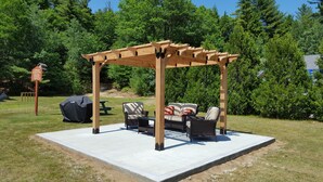 A wooden pergola with outdoor furniture, a picnic table, and a grill. - Eastern Inn & Suites (North Conway)